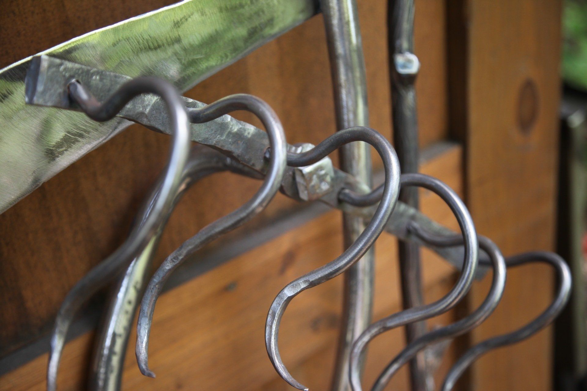 A close up of a wrought iron fence with a wooden background