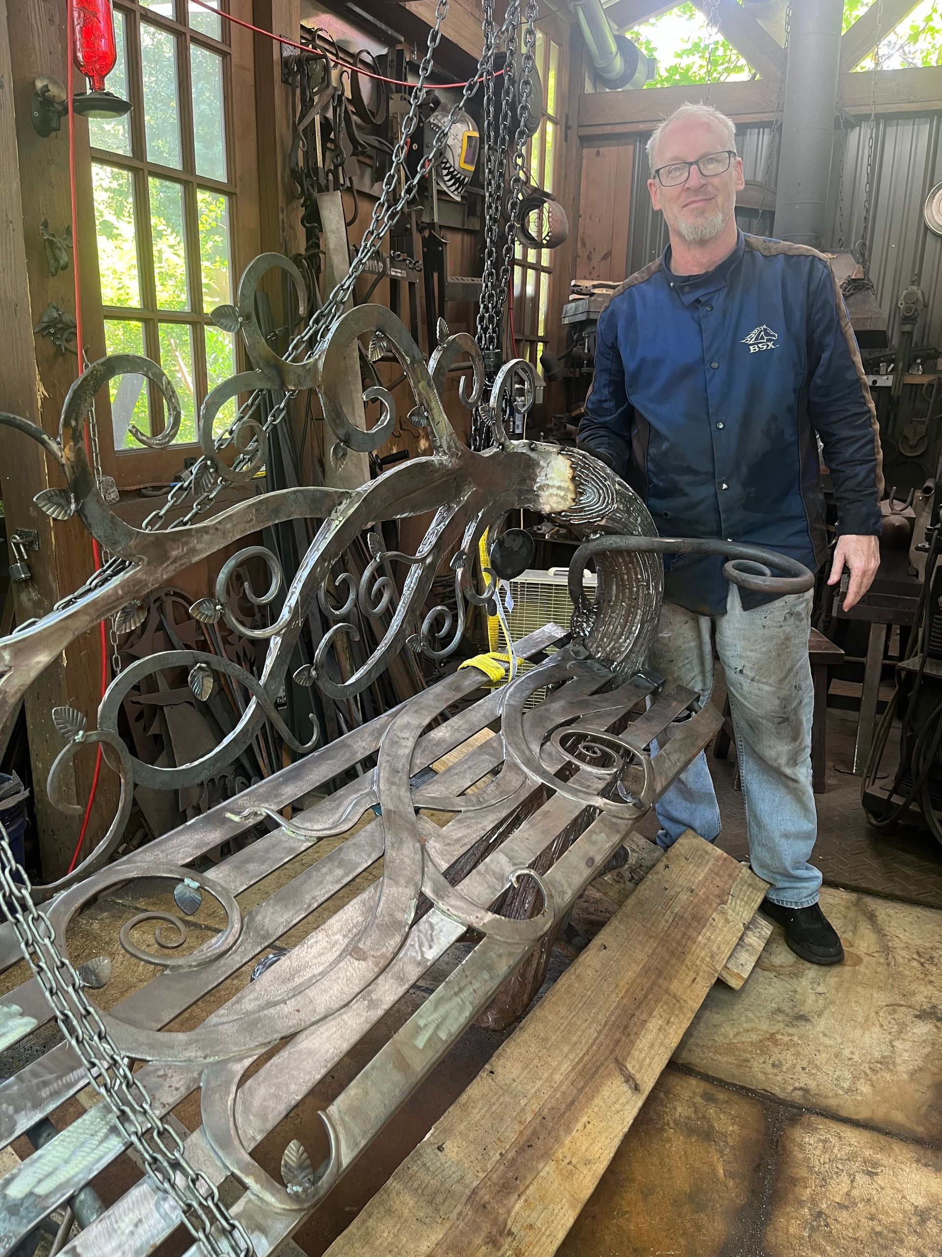 A man is standing next to a wrought iron bench.