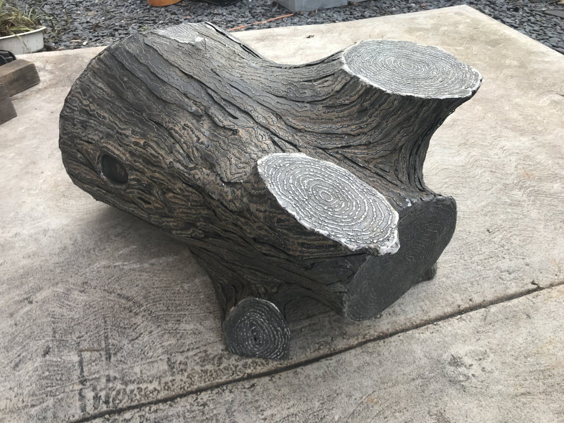 A large piece of wood is sitting on a concrete surface.