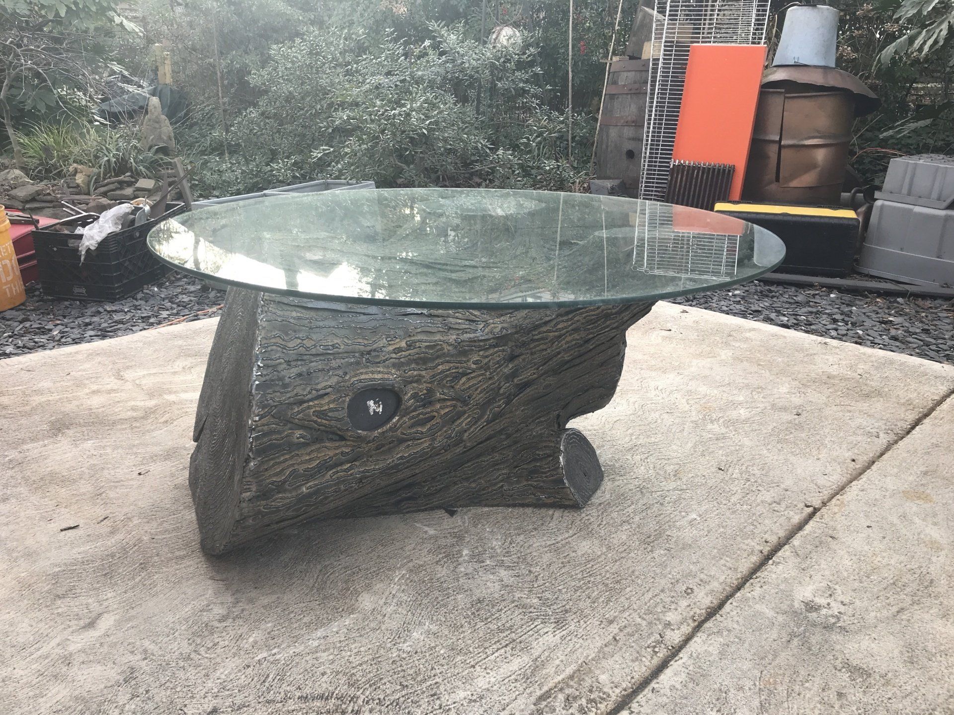 A glass coffee table is sitting on a concrete surface.