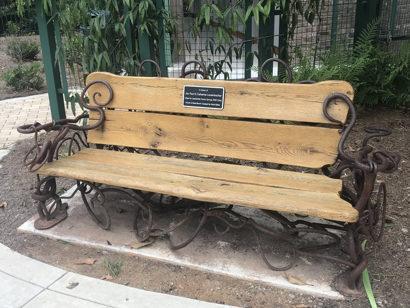 A wooden bench with a metal frame and a plaque on it.