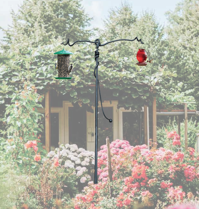 A bird feeder is hanging from a pole in a garden.