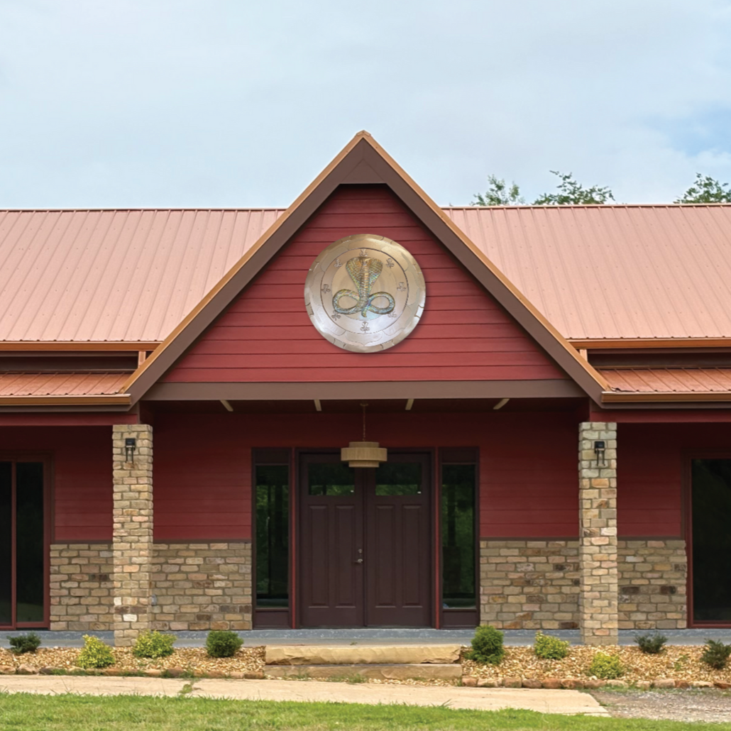 A large white house is surrounded by trees and a lush green lawn.