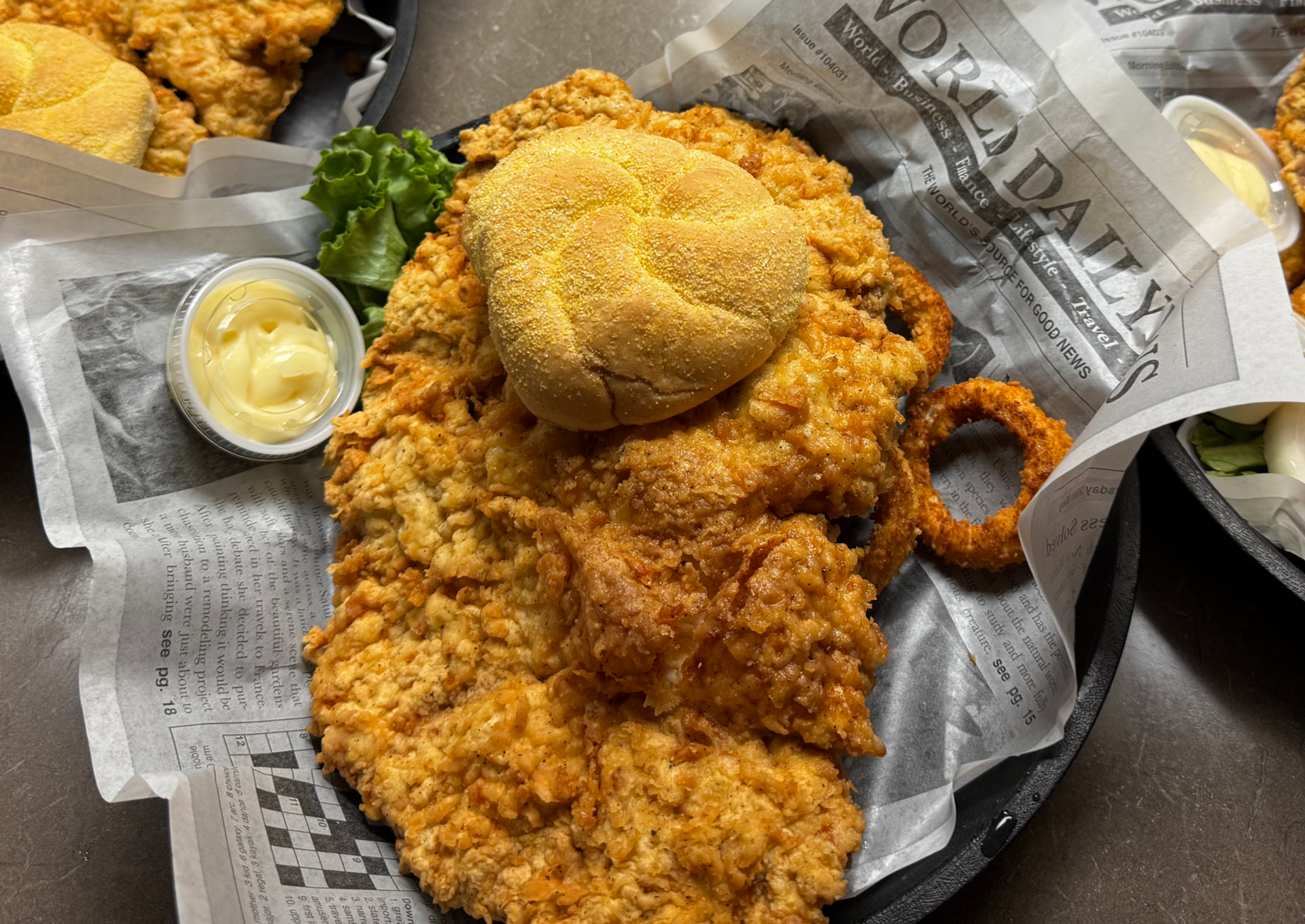 Plated fried chicken with dipping sauce, on newspaper-lined trays. Plated fried chicken with dipping sauce, on newspaper-lined trays.