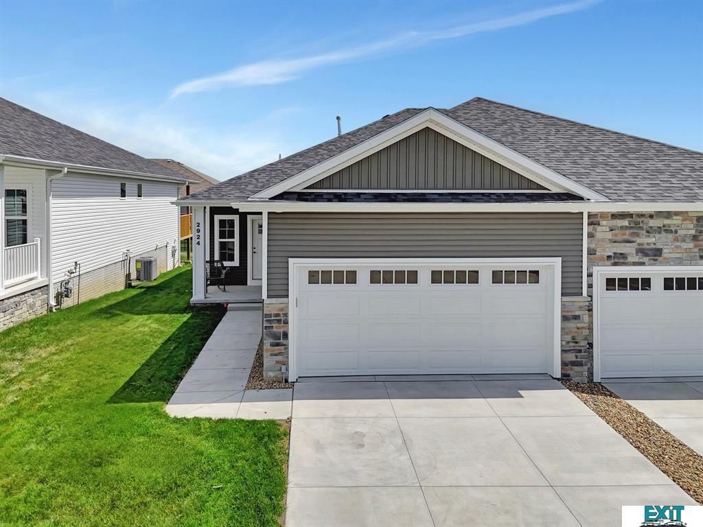 House exterior with white garage door and gray siding, blue sky.