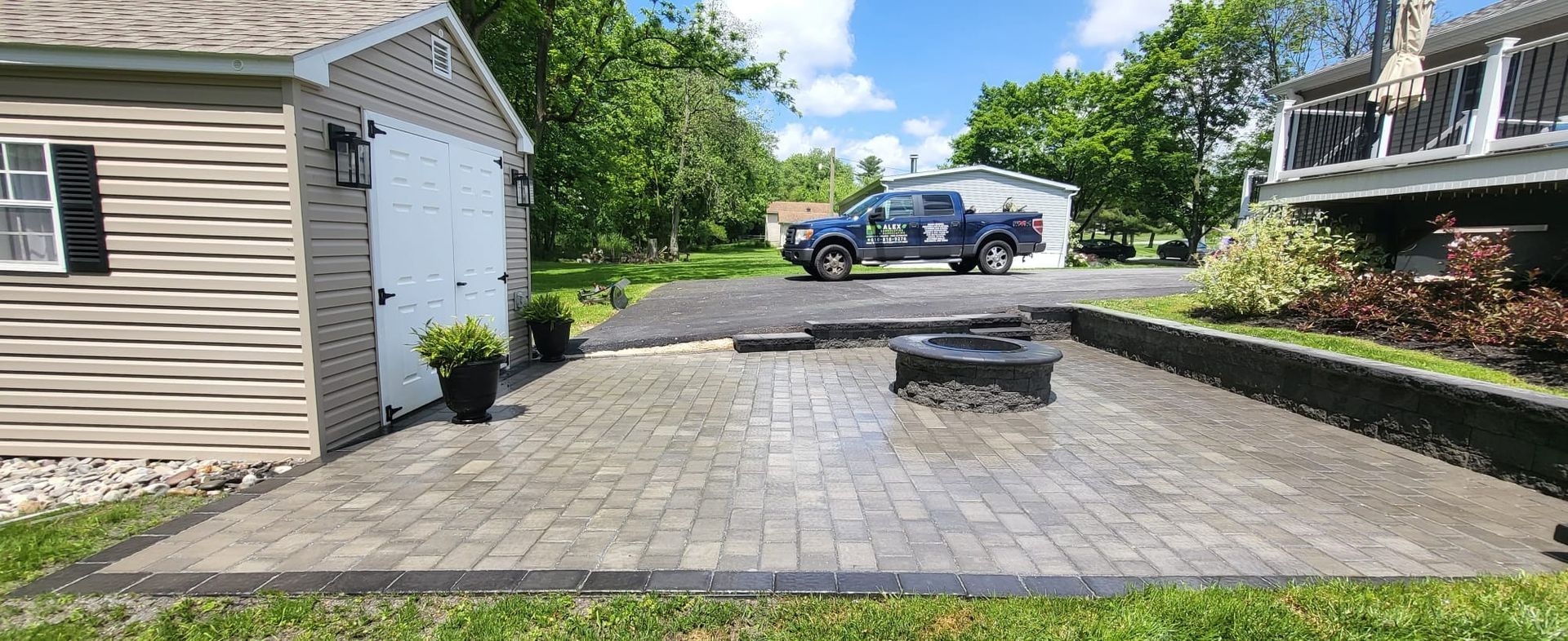 A truck is parked in a driveway next to a brick patio.