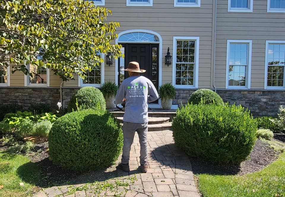 A man in a hat is standing in front of a large house.