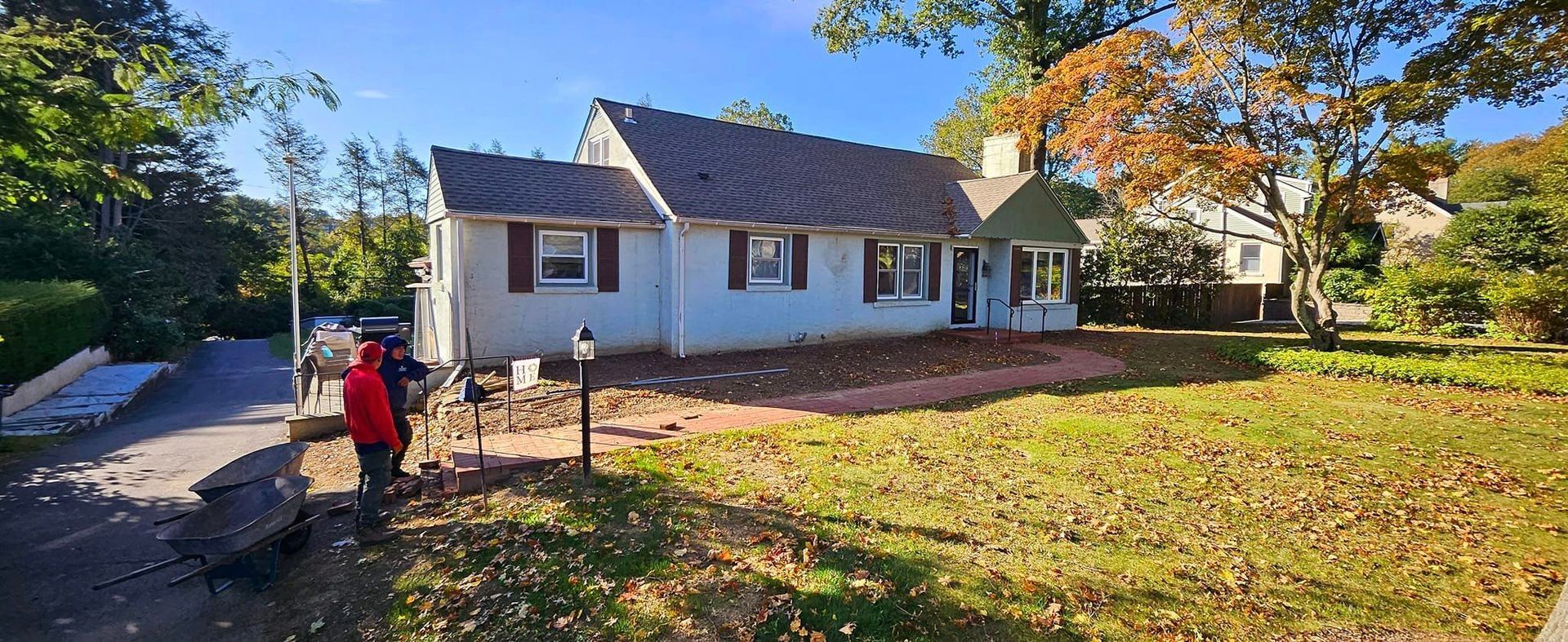 A group of people are standing in front of a white house.