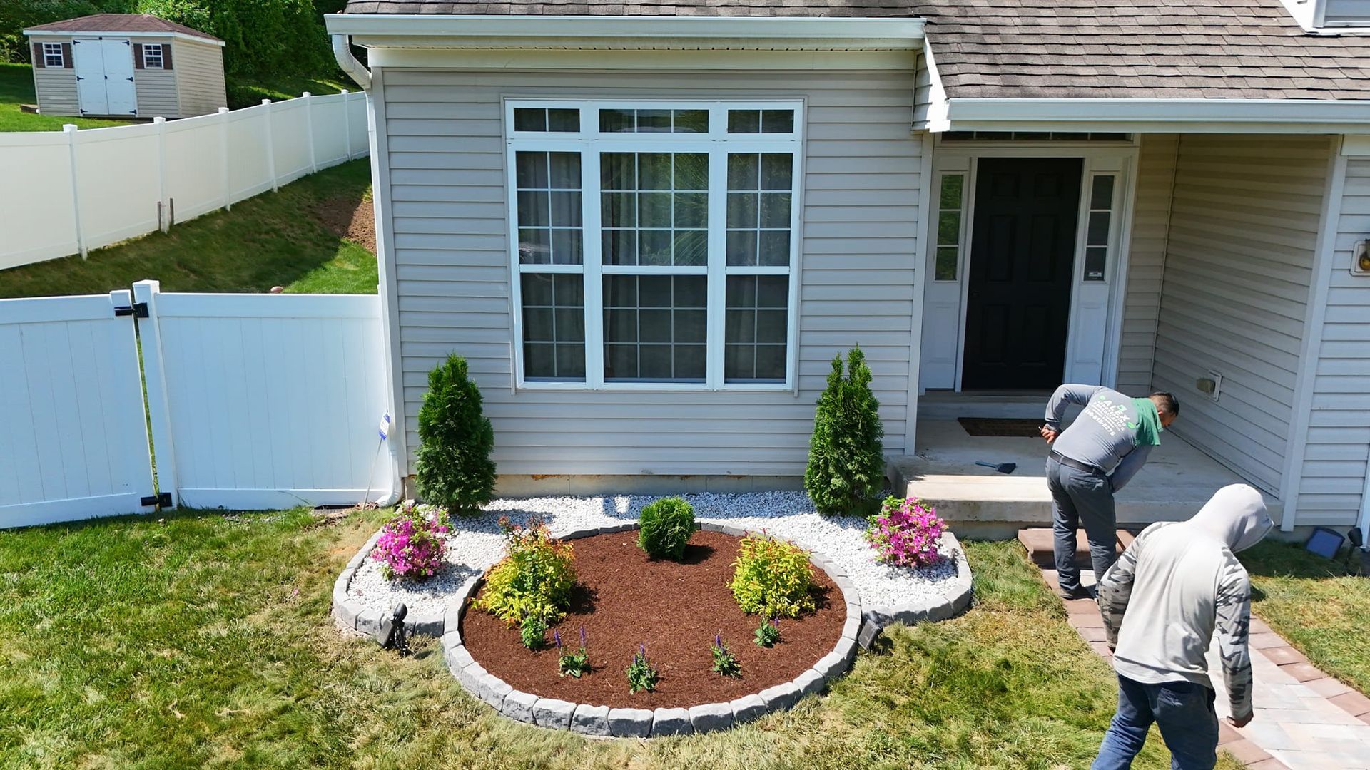 A couple of men are standing in front of a house.