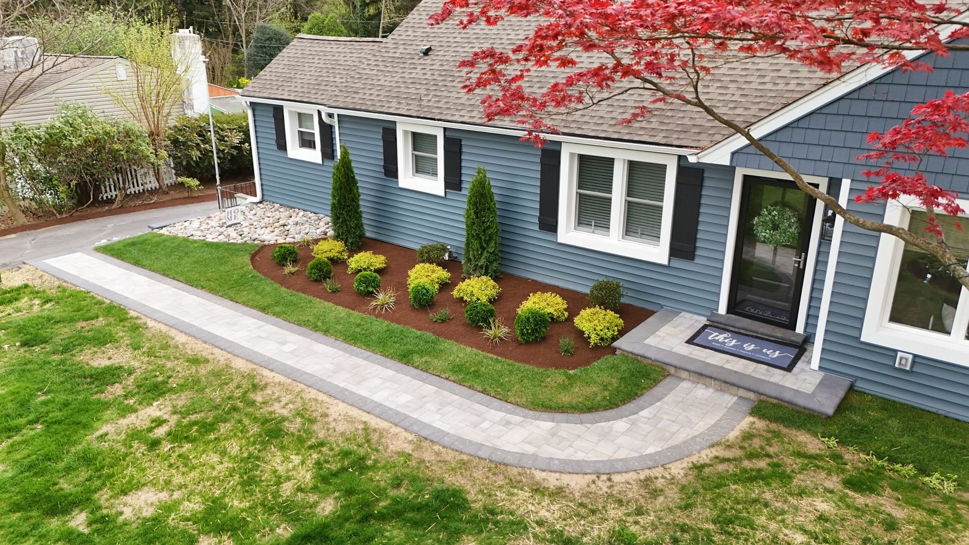 An aerial view of a blue house with a walkway leading to the front door.