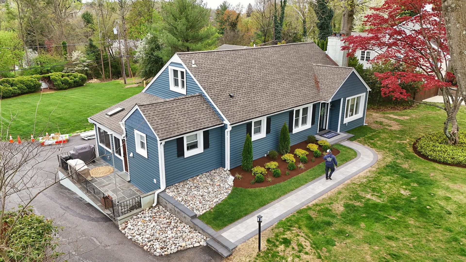 An aerial view of a blue house with a man walking in front of it.