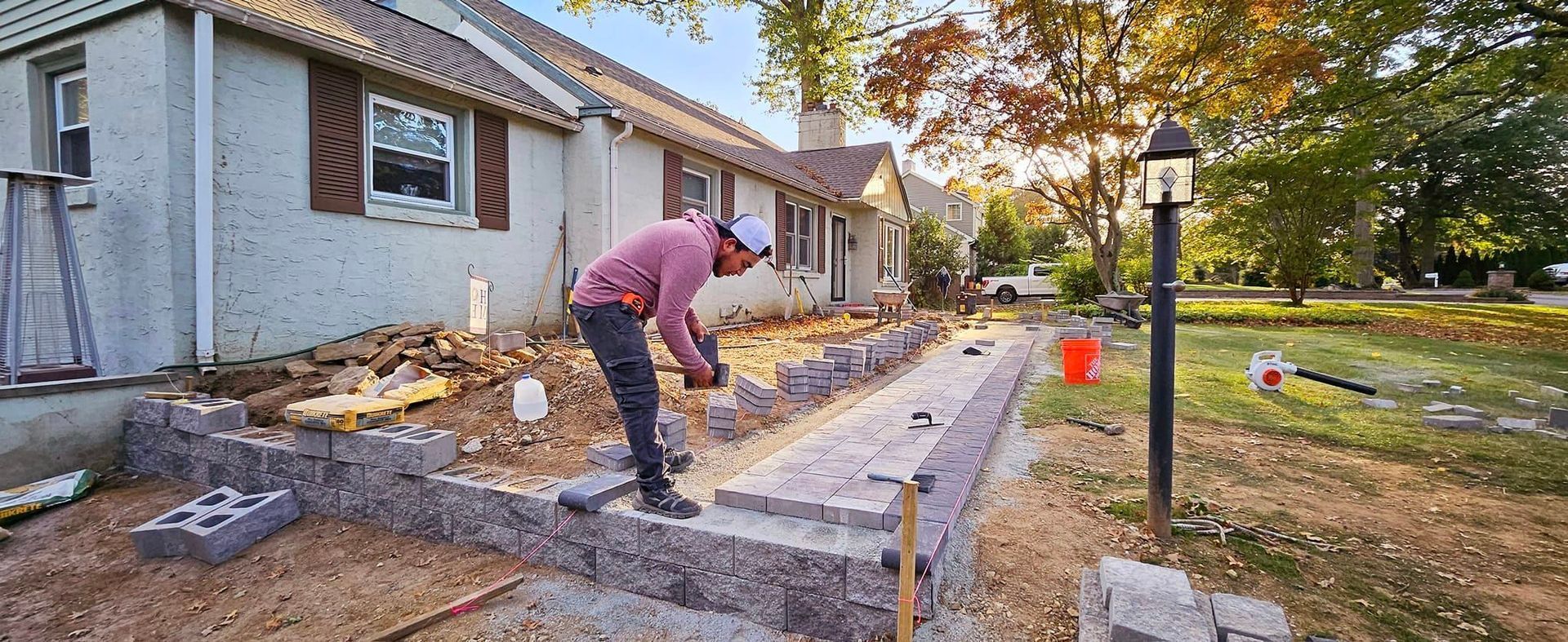 A man is working on a sidewalk in front of a house.