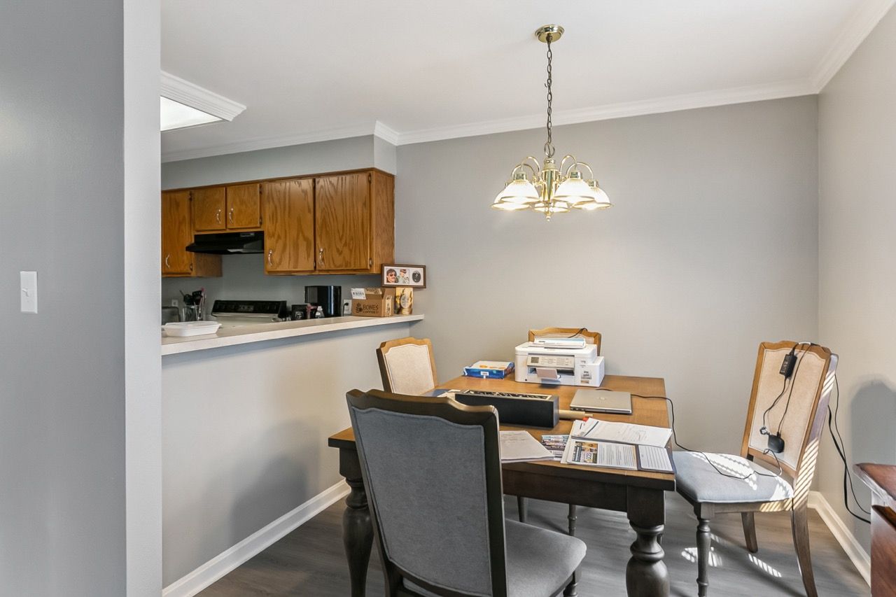 Dining area with a table and chairs, adjacent to a kitchen with wooden cabinets.