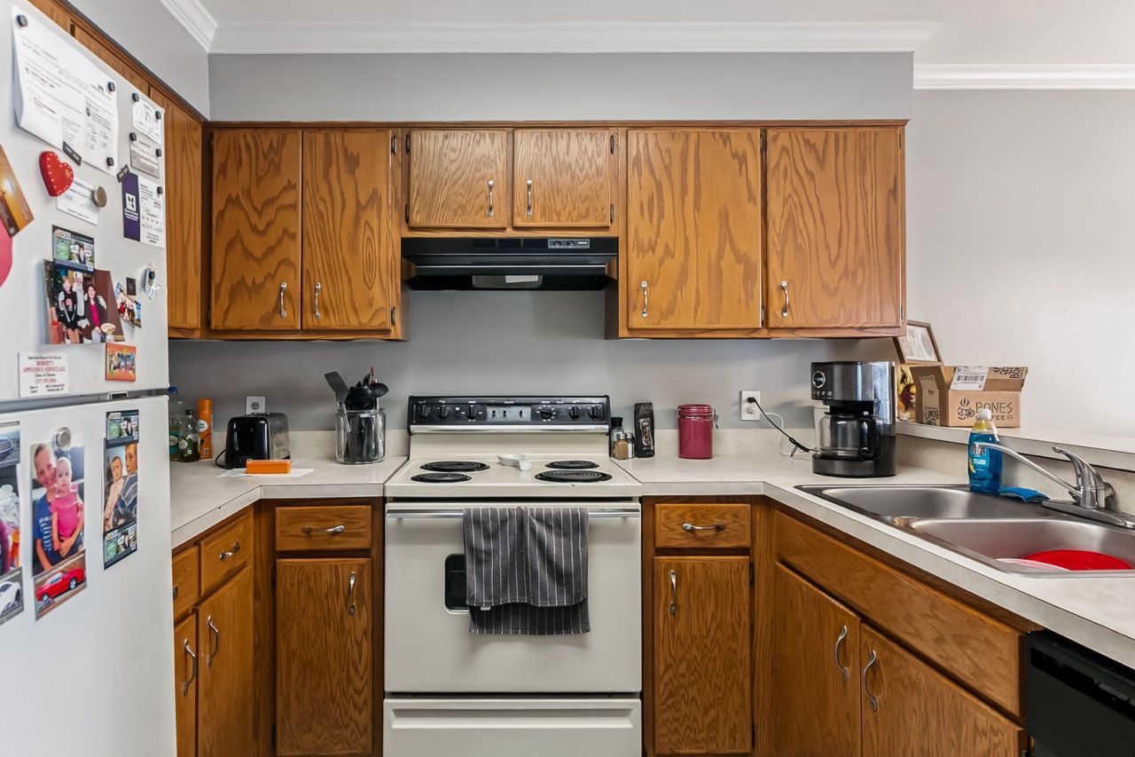 A small kitchen with wooden cabinets, white appliances, and a gray countertop.