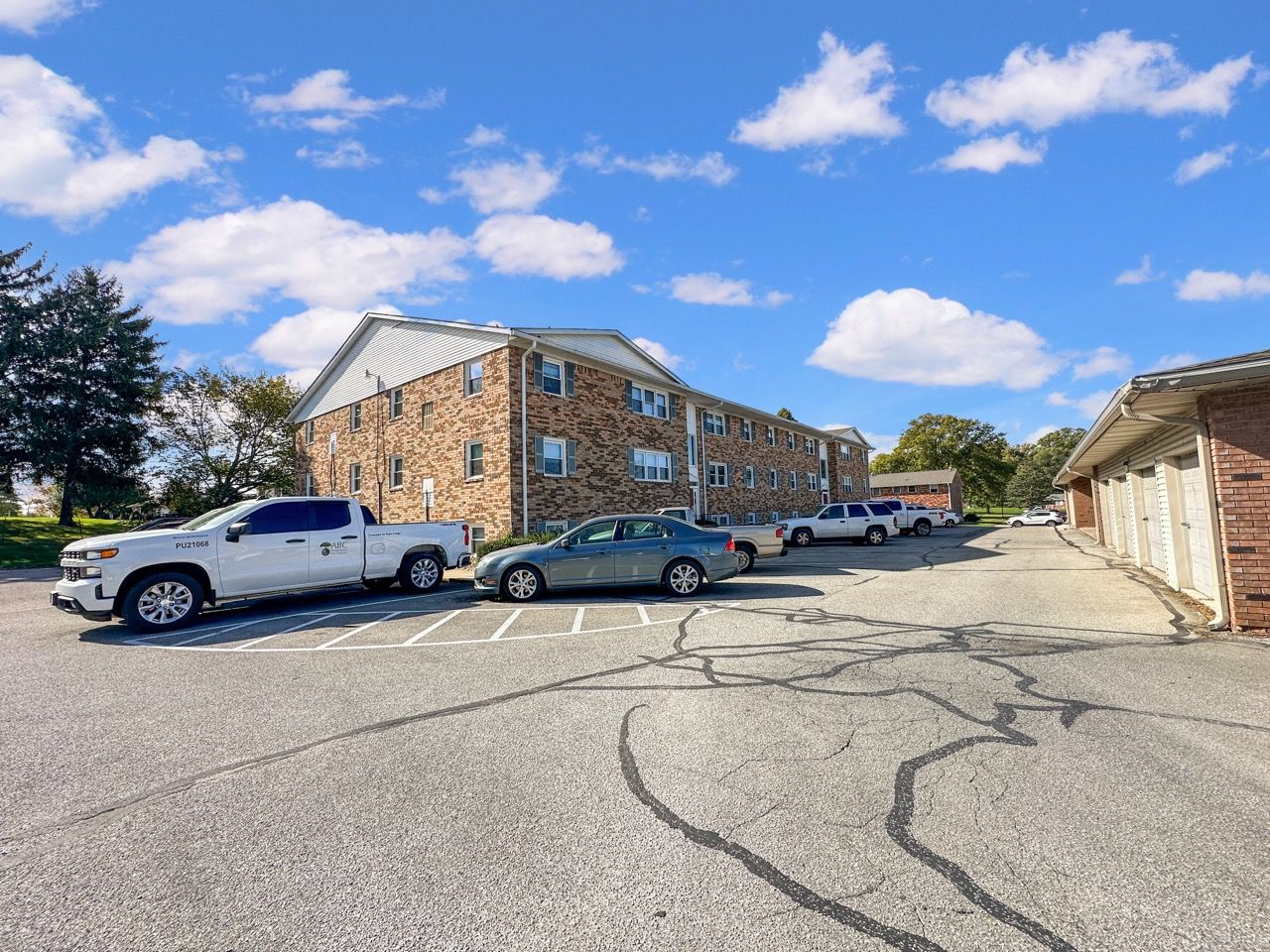 Apartment building with parked cars in front on a sunny day.