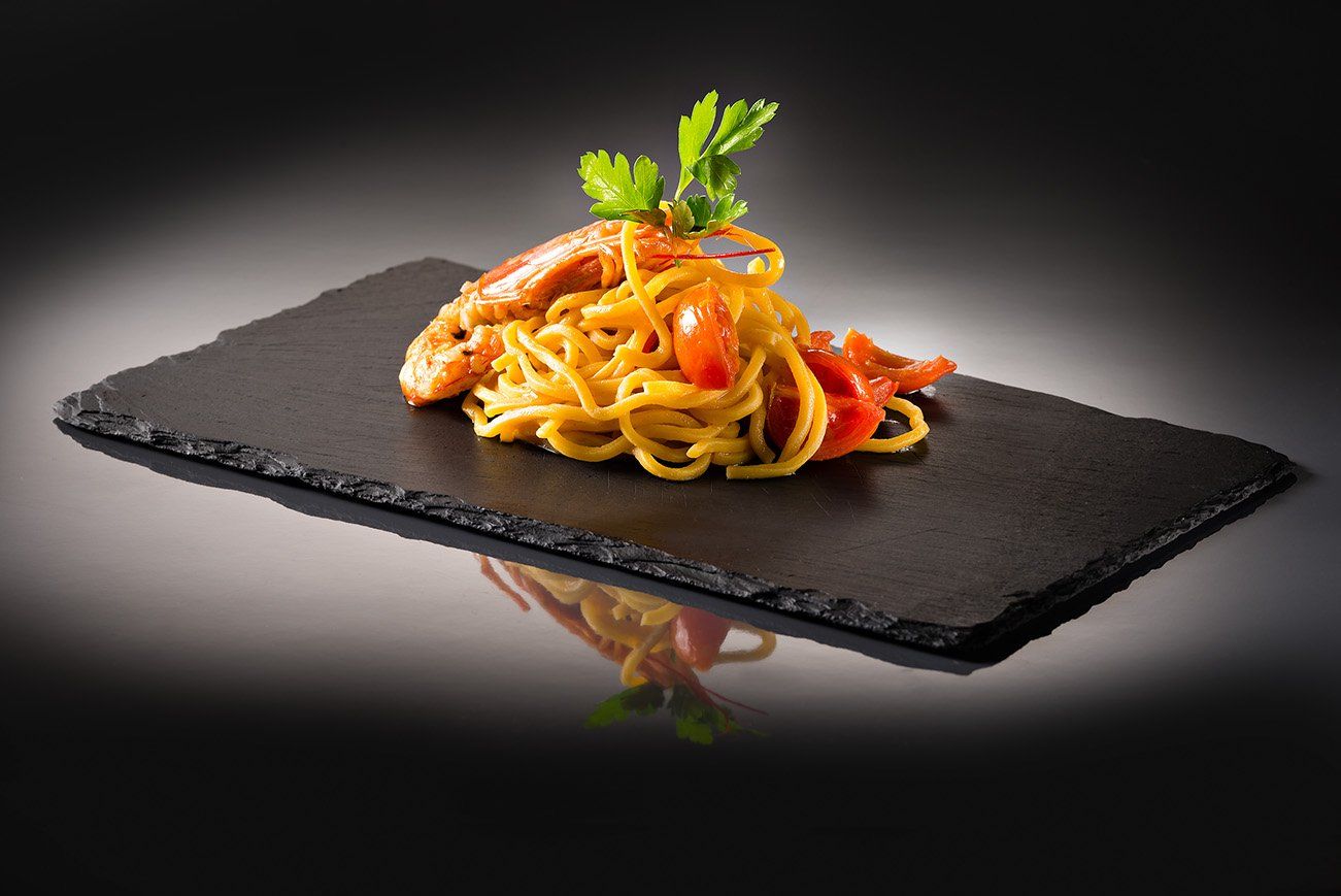 spaghetti with scampi on a black plate
