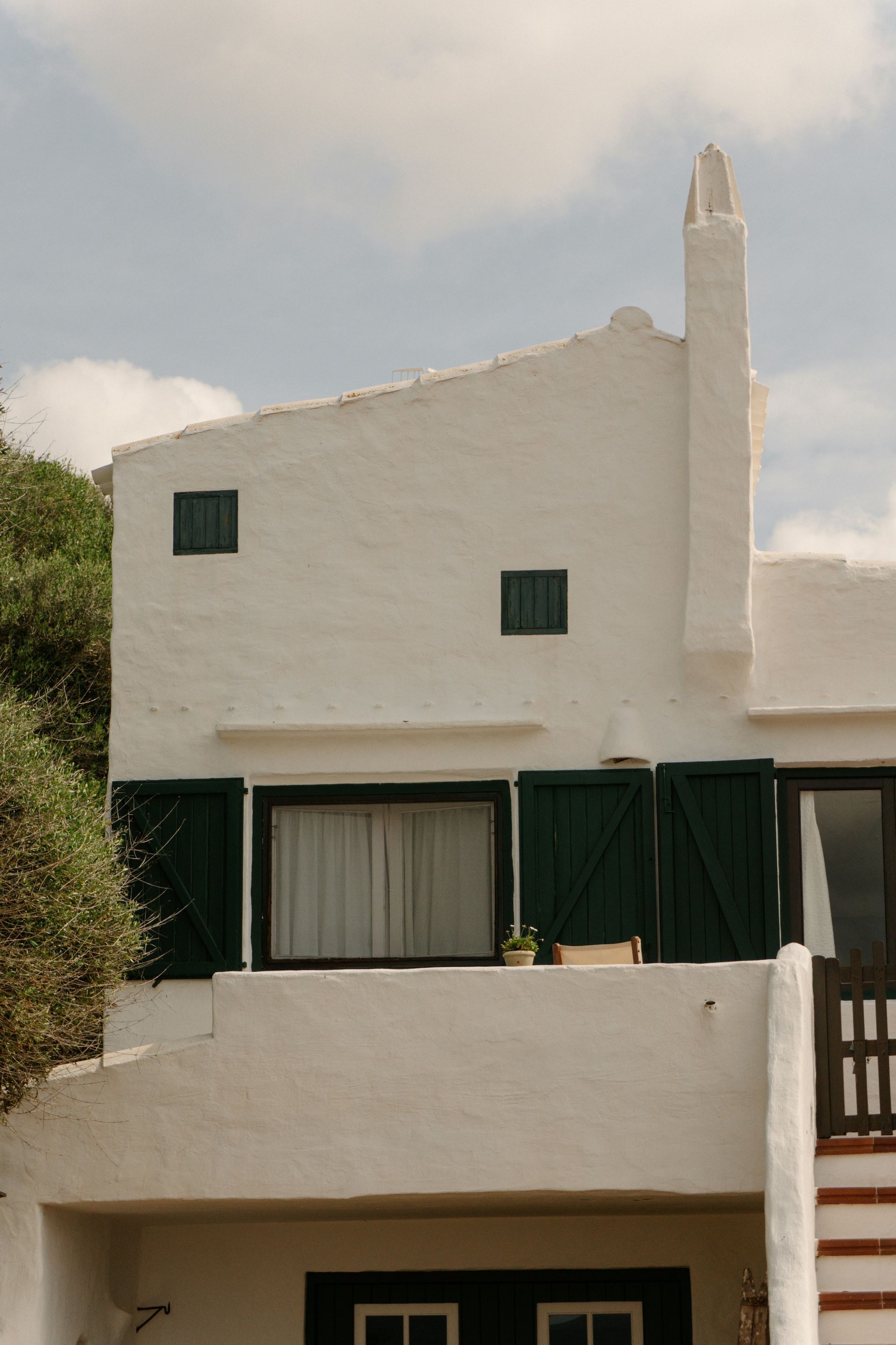 A white house with green shutters and a chimney.