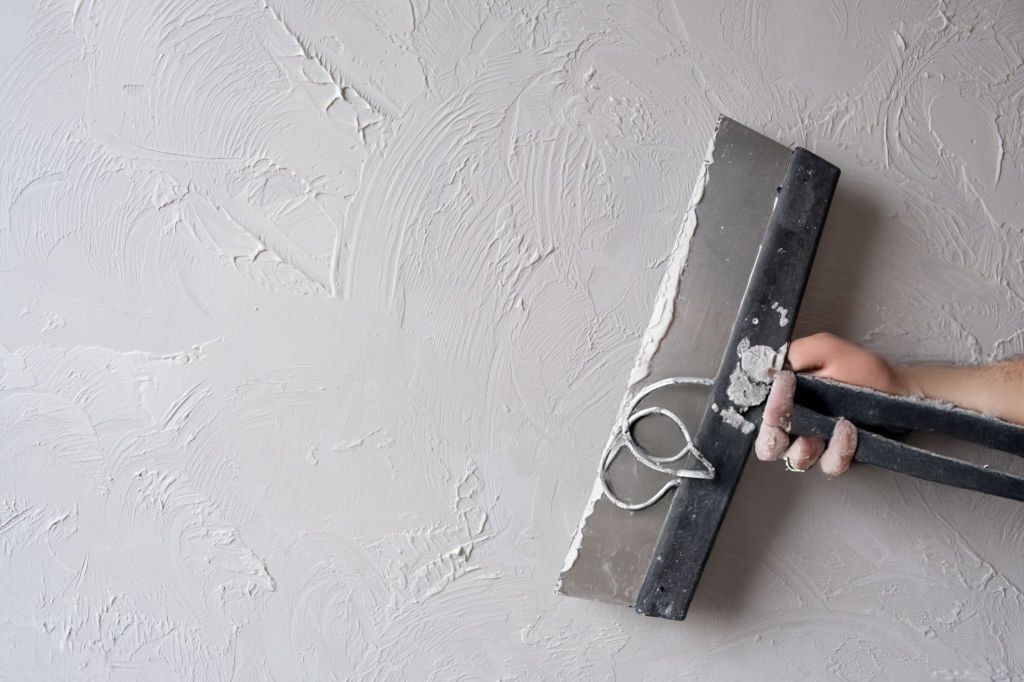 A person is plastering a wall with a spatula.