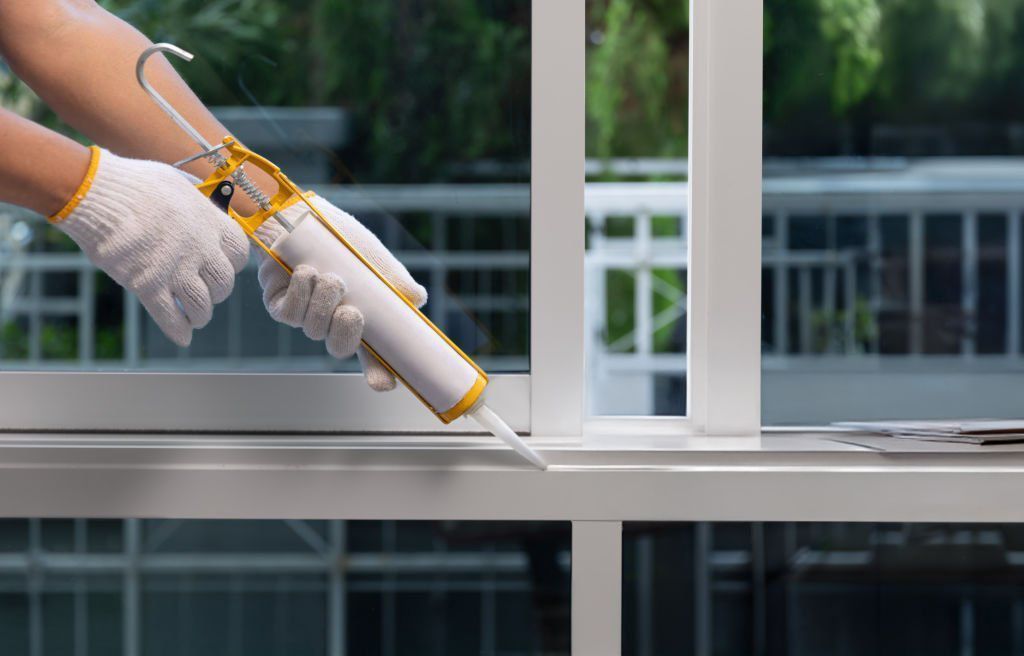 A person is applying caulk to a window frame.