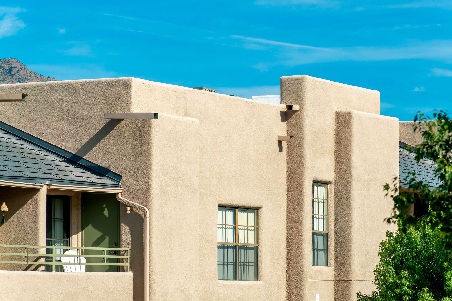 Beige stucco building with flat roof, against a blue sky.