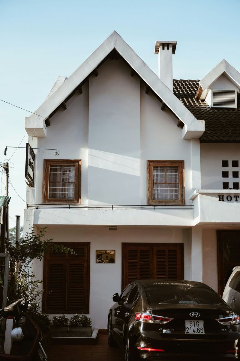 A black car is parked in front of a white house.