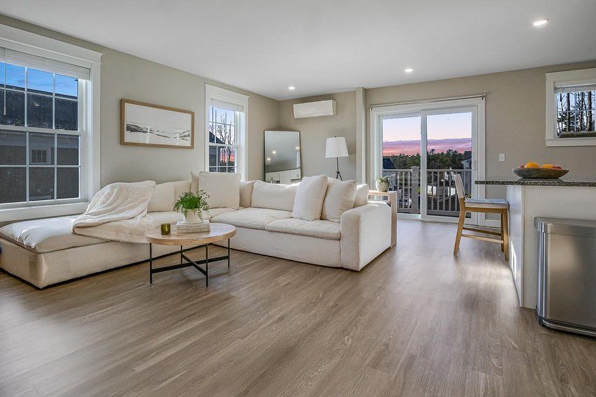 Cozy living room with large white sectional sofa, light wood floors, and balcony access.