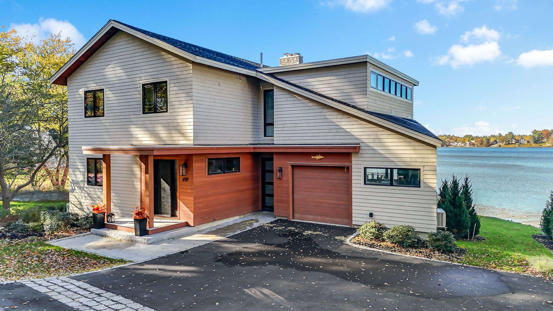 Two-story house with brown accents and a garage, facing a lake.