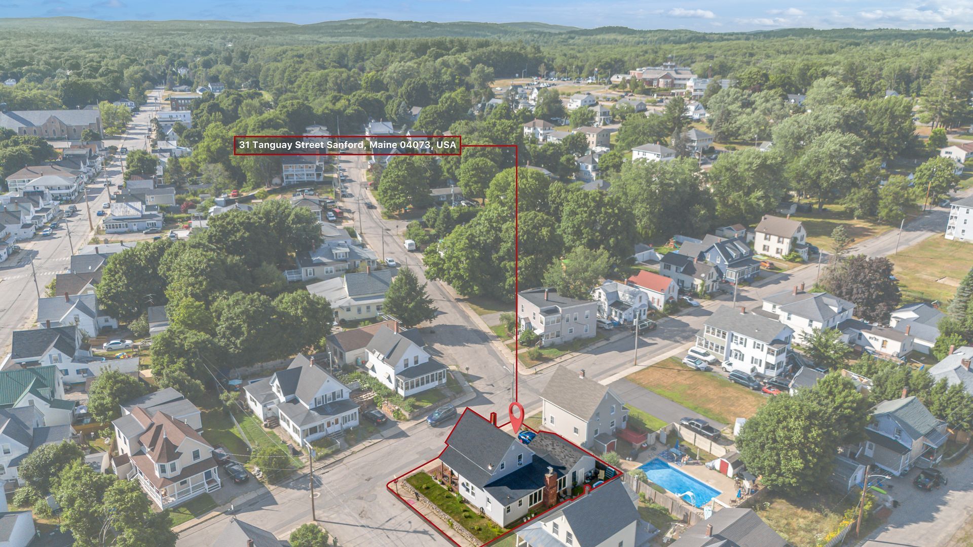 Aerial view of a residential neighborhood with houses, trees, and a swimming pool.