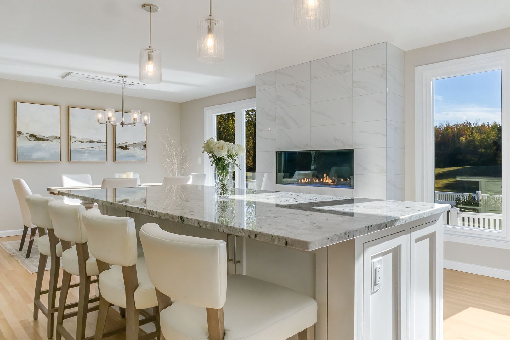 Modern kitchen with large island, seating, fireplace, and scenic window view.