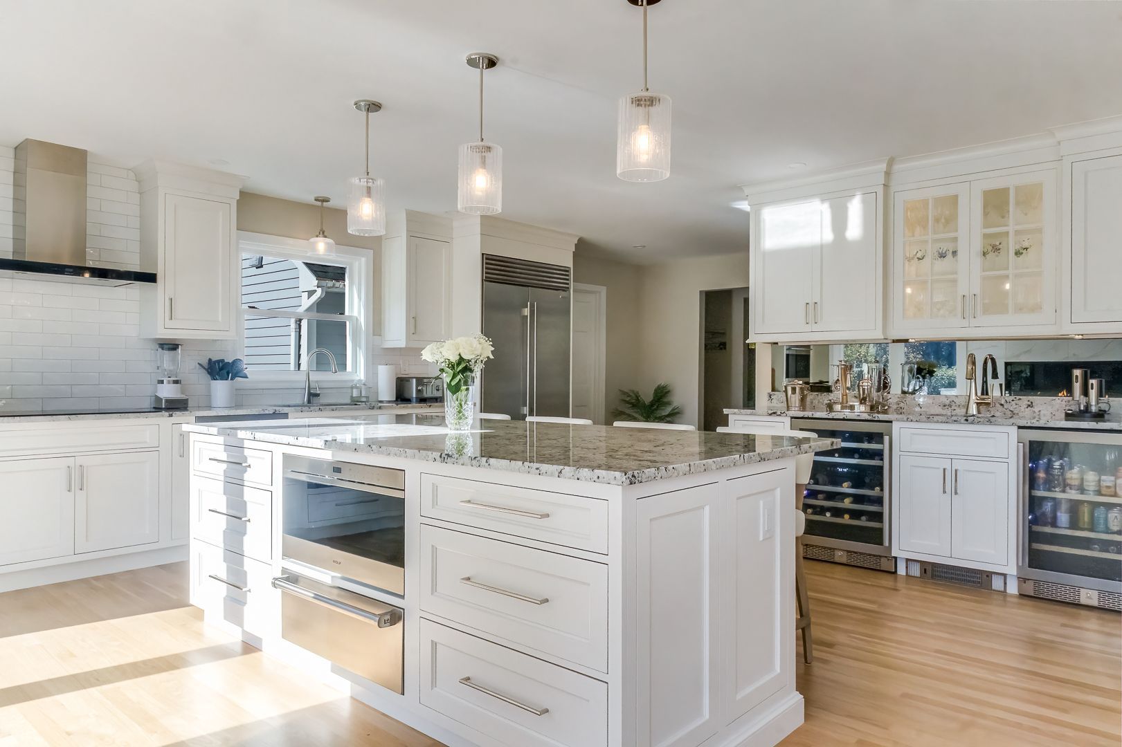 Bright, modern kitchen with white cabinets, large island, stainless steel appliances, and pendant lights.