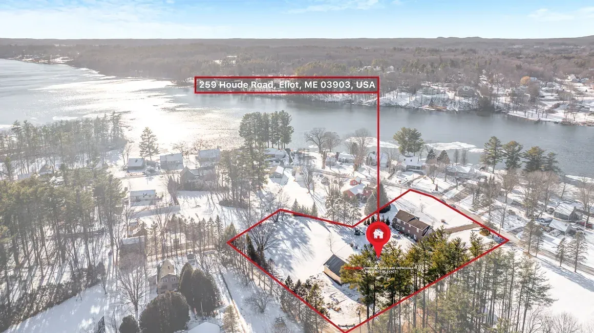 Aerial view of a house on snow-covered land near a lake, marked with a location pin and address.