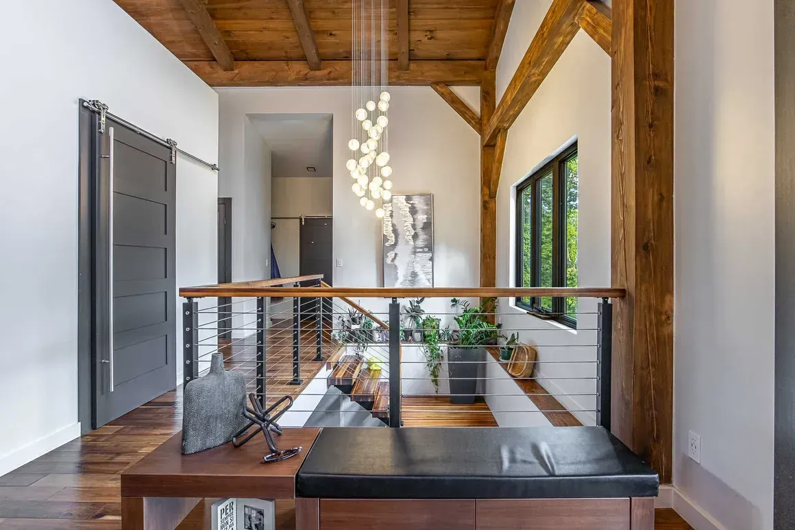 Hallway with wooden beams, modern light fixture, and a bench.