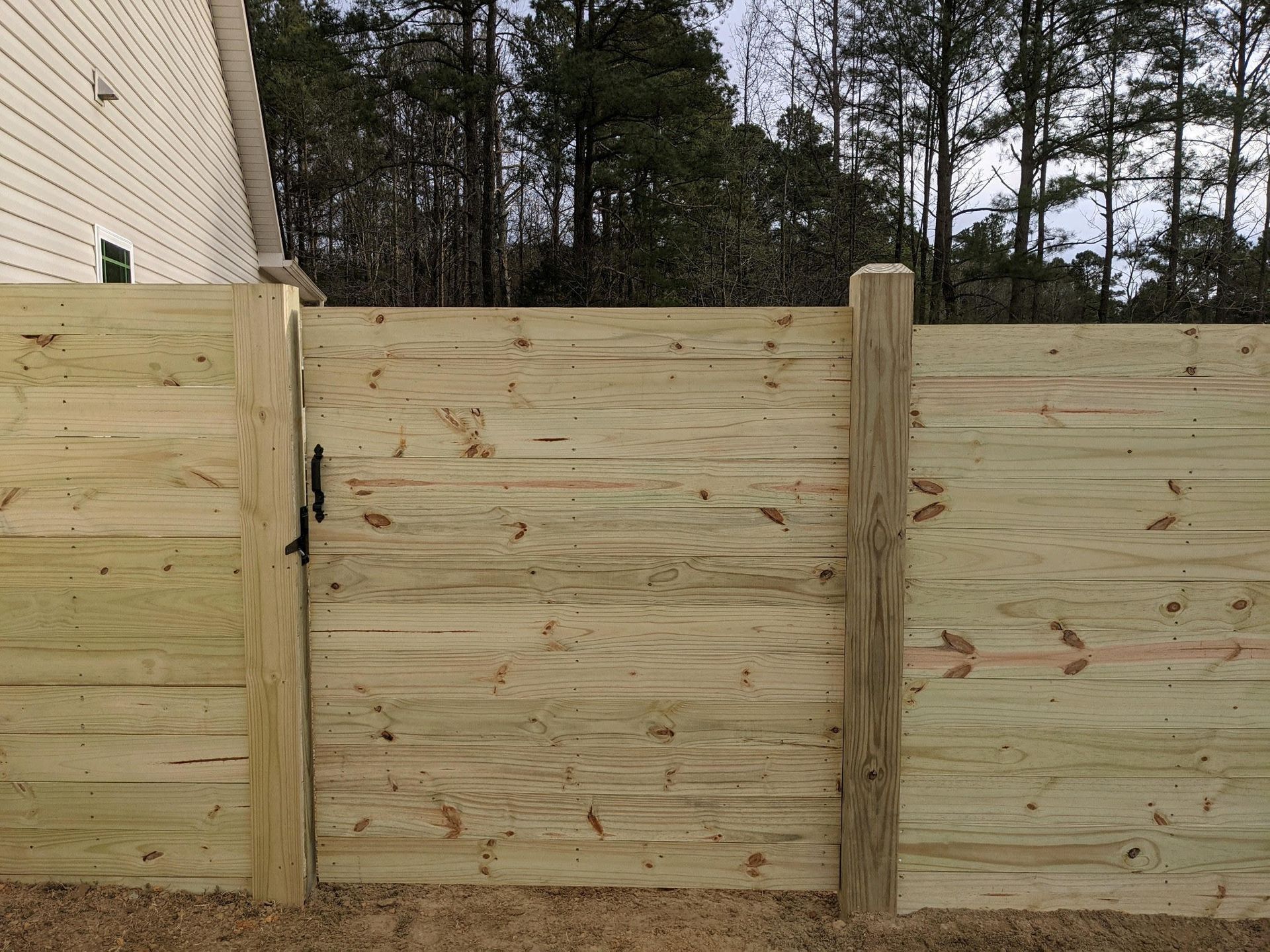 A wooden fence with a gate in the backyard of a house.