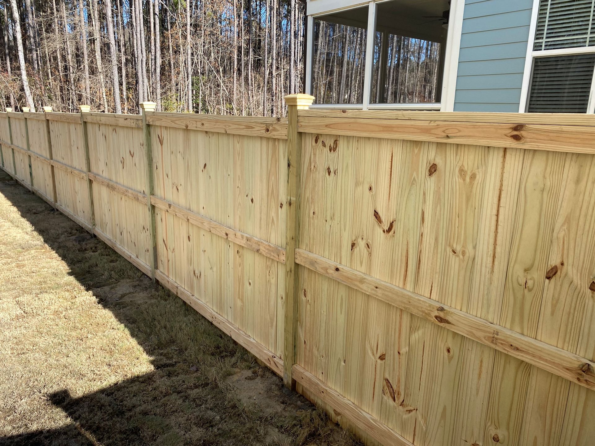 A wooden fence is in the backyard of a house.
