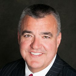 A man in a suit and tie is smiling for the camera.