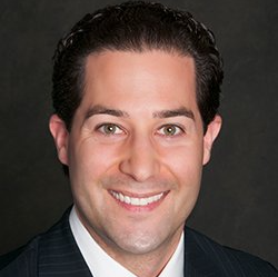 A man in a suit and tie is smiling for the camera.