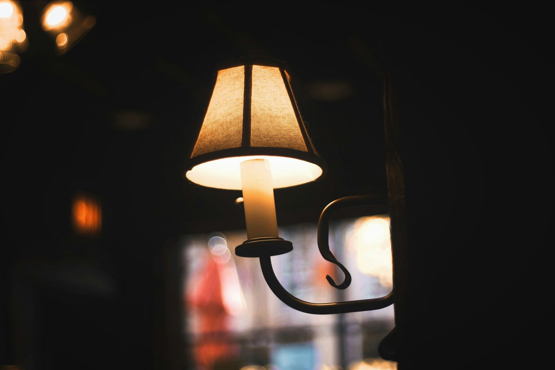 A lamp with a candle in it is lit up in the dark.