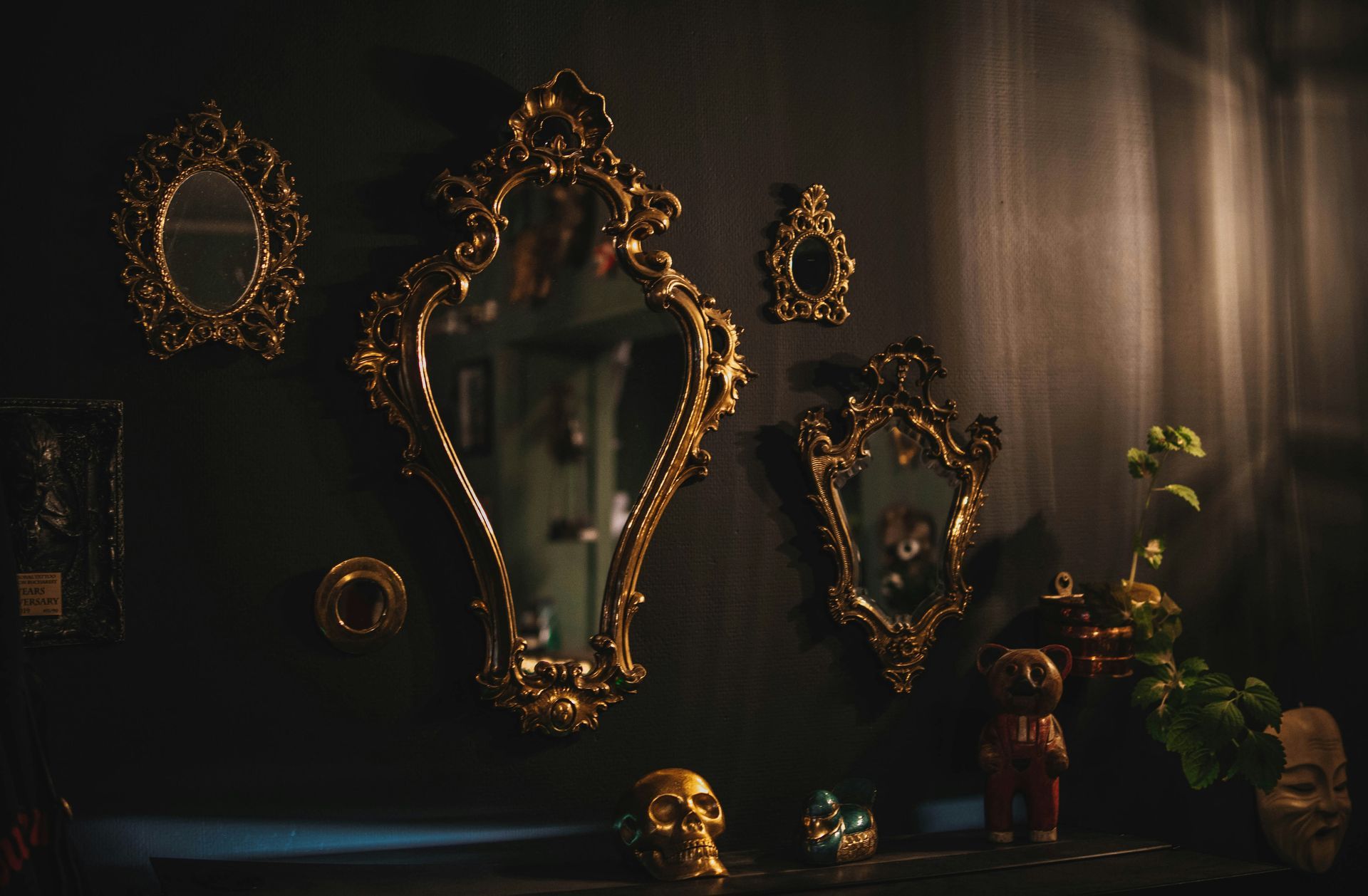 A group of mirrors hanging on a wall in a dark room.
