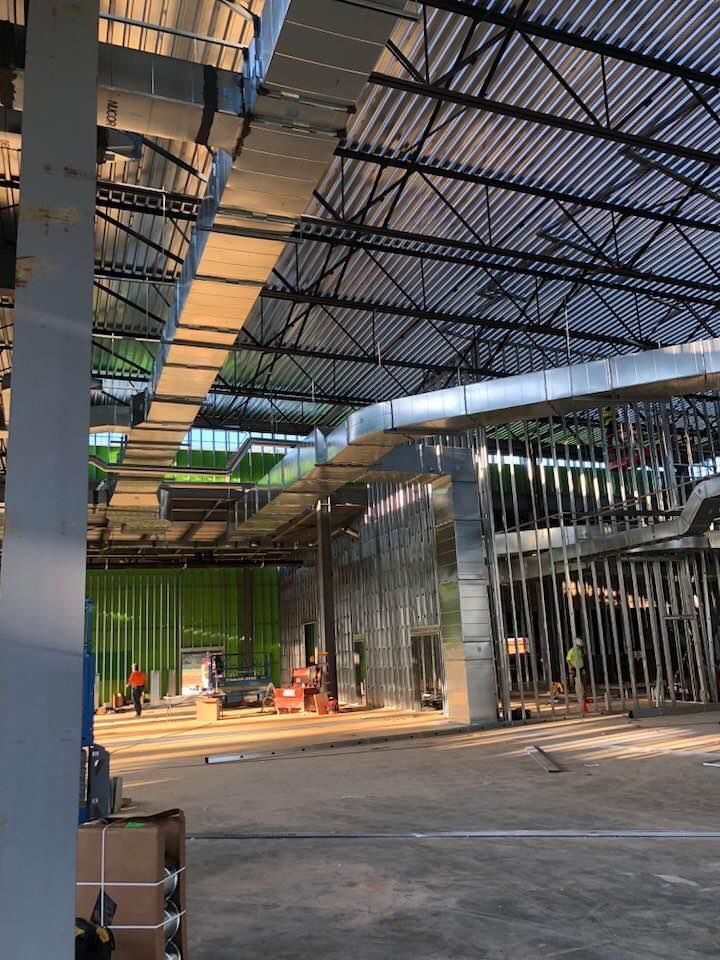 Construction site with exposed ductwork and metal framing; concrete floor.