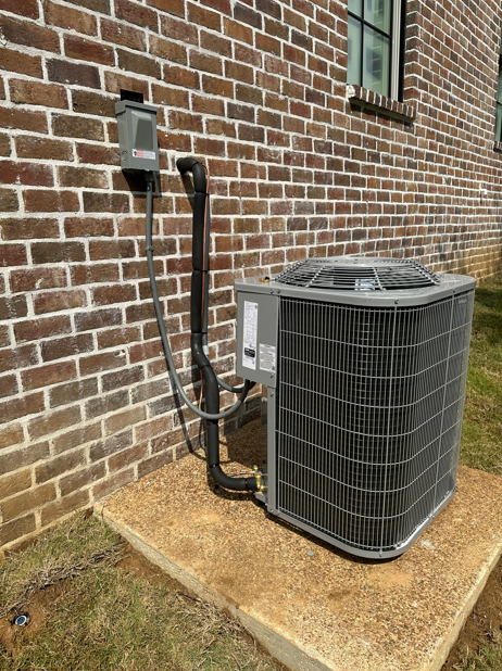An air conditioning unit next to a brick building.
