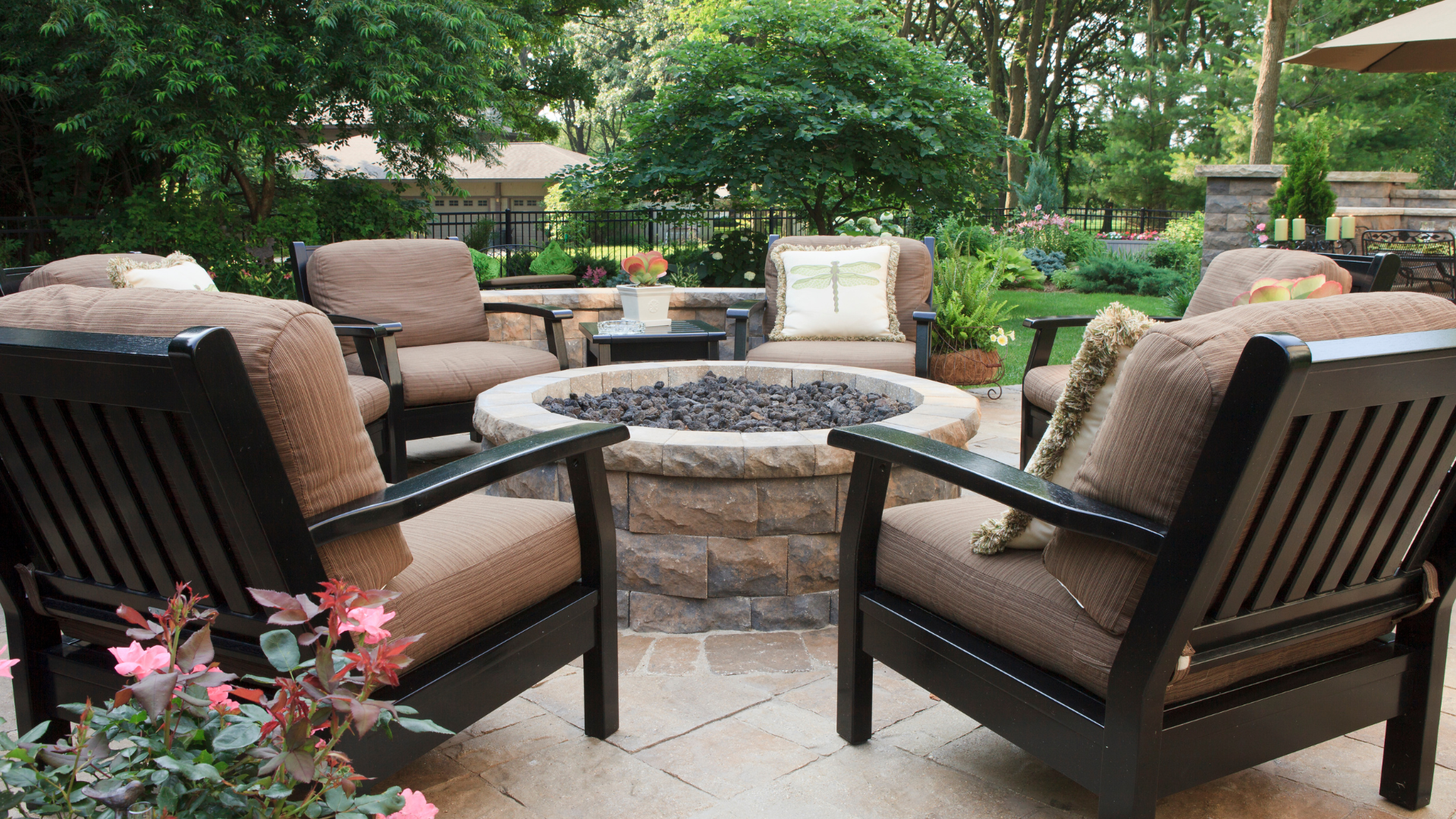 There is a fire pit in the middle of the patio surrounded by chairs.