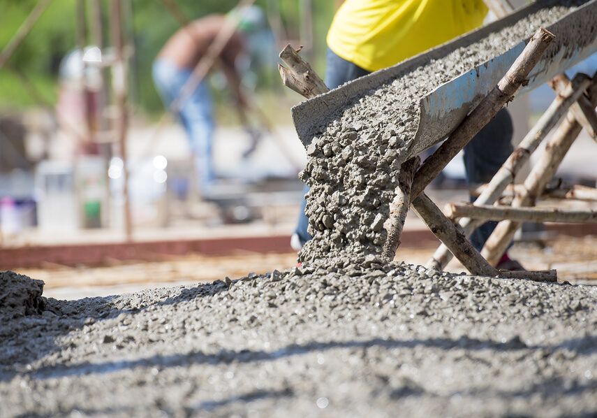 A man is pouring concrete into a wheelbarrow at a construction site.