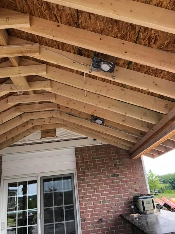 Wooden roof under construction with two recessed lights, brick wall, and sliding glass door.