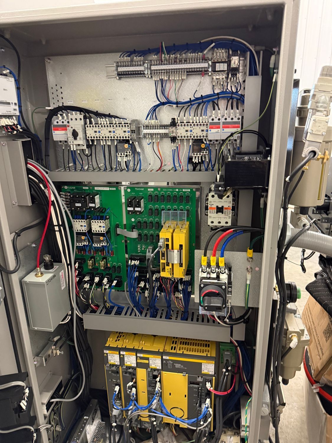Control panel with wires, circuit breakers, and electronic components, housed in a metal cabinet.