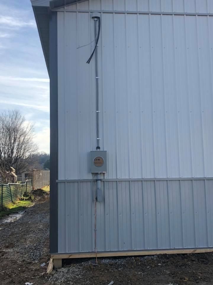 Metal building with electrical conduit and box mounted on the exterior.