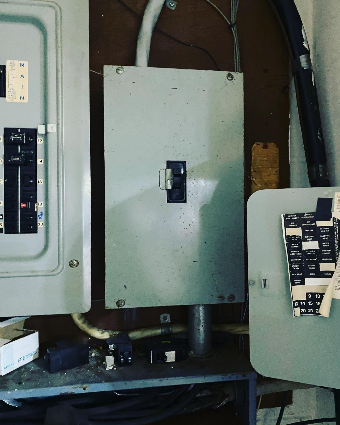 Gray electrical panel with a closed breaker, mounted on a wall.