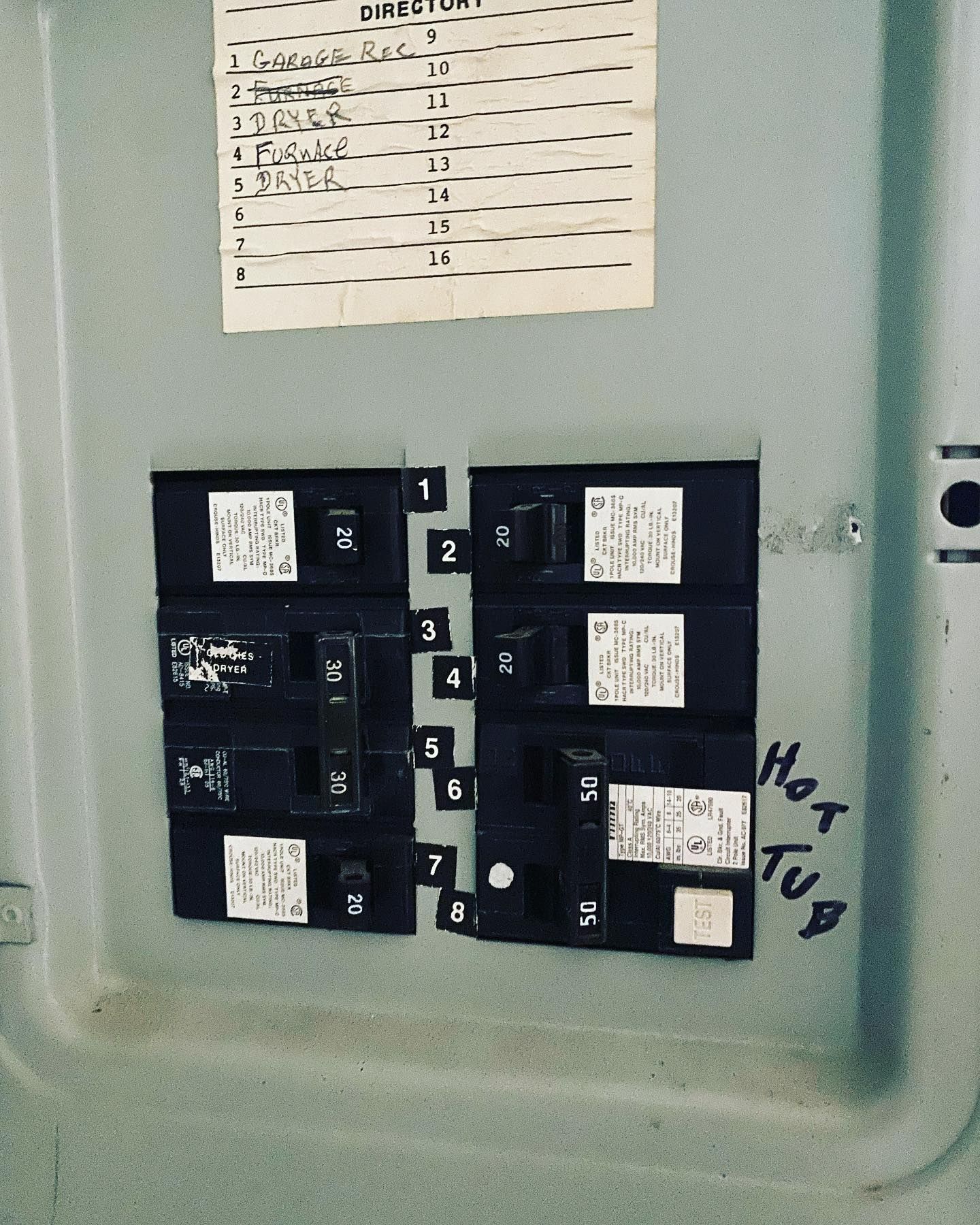 Electrical circuit breaker panel with labeled breakers. A handwritten 