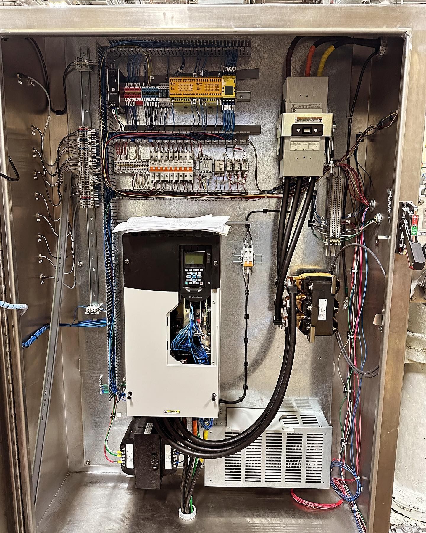 Electrical control panel with wiring, circuit breakers, and a variable frequency drive.