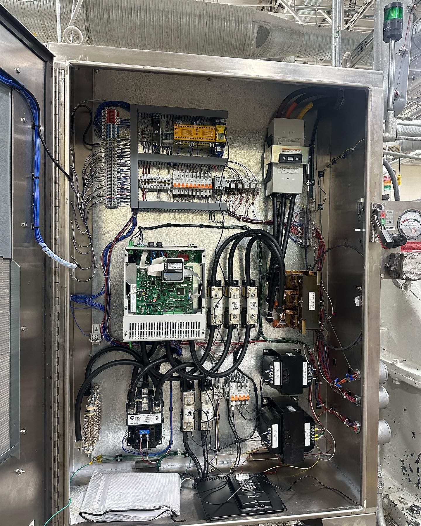 Electrical control panel with wires, circuit breakers, and components inside a metal cabinet.