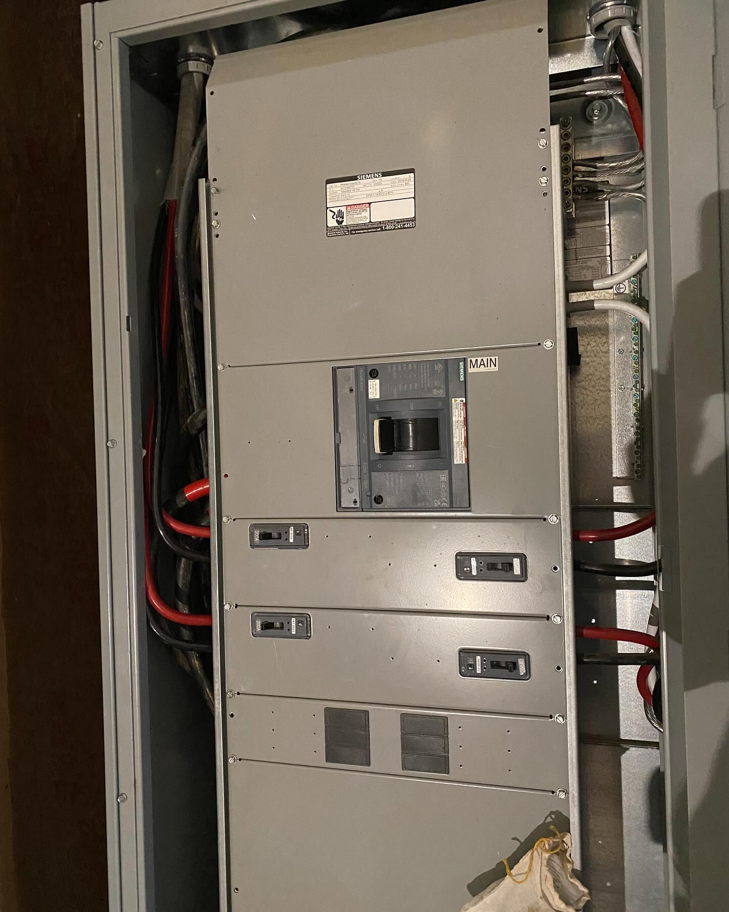 Electrical panel with open cover, showing breakers and wiring.